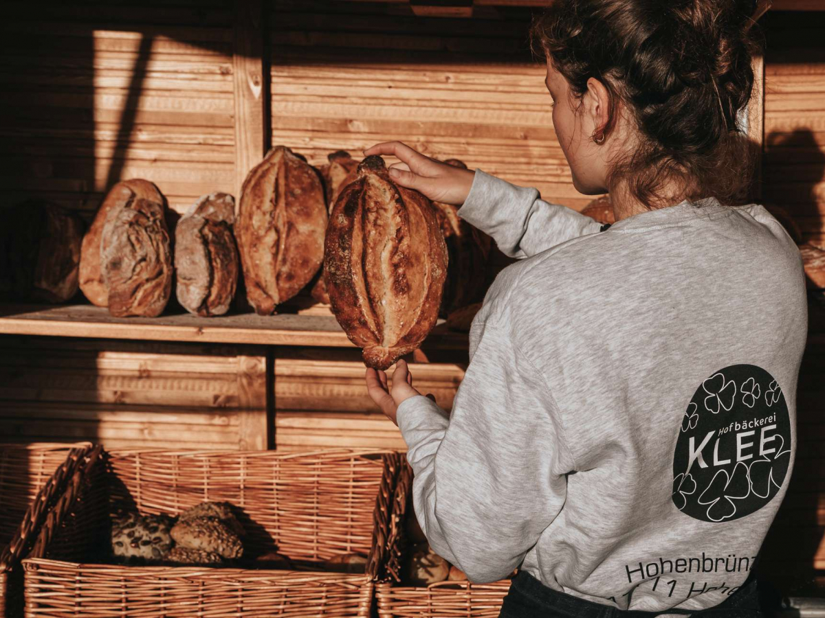 Frau holt Brötchen aus dem Regal